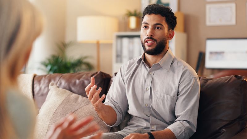 A man talking openly in a warm, relaxed therapy room