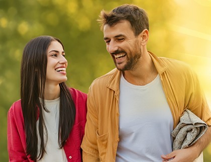 A smiling couple walking together in warm sunlight